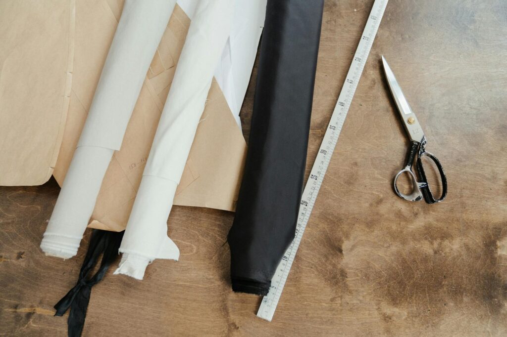 Fabric rolls, ruler, and cutting shears on a fashion design worktable